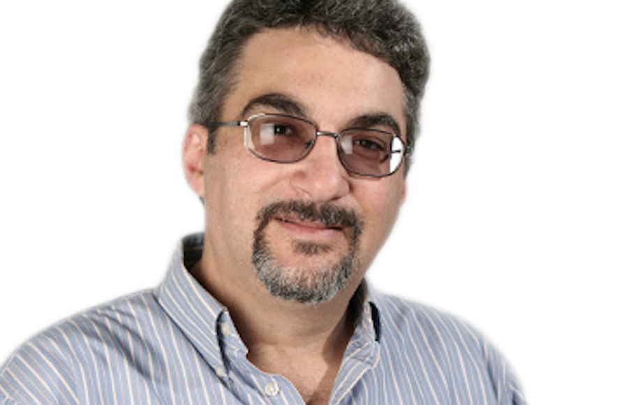 Man with glasses and goatee smiling against a light background